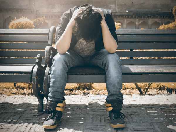 man in black shirt and gray denim pants sitting on gray padded bench