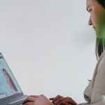 crop woman browsing laptop in room